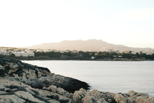 Coastal town nestled between rocky shores and distant mountains at sunrise