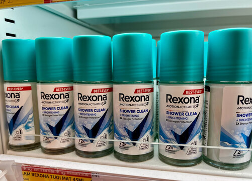 A row of Rexona deodorant spray bottles is displayed on a retail shelf. The bottles feature a turquoise cap and a clear design, emphasizing cleanliness and freshness.