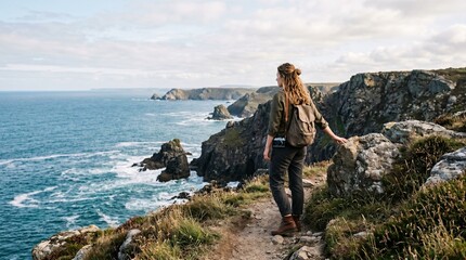 Obraz premium Woman hiker looking at scenic coastal cliffs and ocean waves on a sunny day.