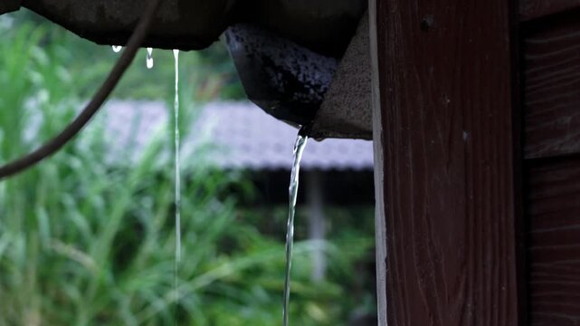 Rainy Season Ambiance: Raindrops dripping from Roof, Water on Pavement and Green Grass Details, Terracotta Wind Chime and Satellite Dish in Monsoon Weather.