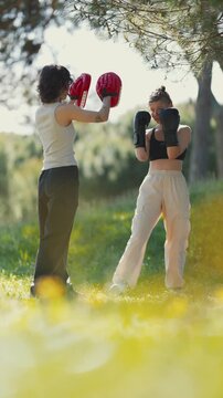 Young woman training boxing outdoors with personal trainer