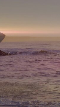 Vertical video: Board entering, surfer walking shore with board post-surf, motion splashes sports