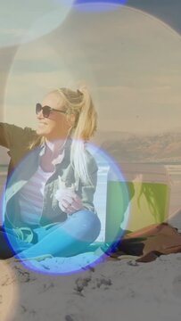 Vertical video: Food woman on beach reacting to cue, sharing snack, sipping red cup, lens flares
