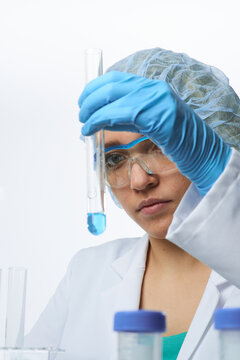 Young european female scientist holding test tube with blue solution during laboratory analysis