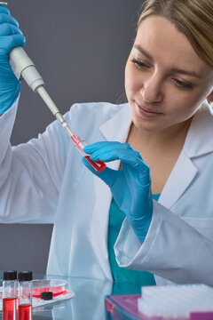 Young european female scientist using micropipette to transfer cell culture into microcentrifuge tube