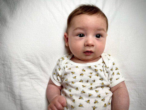 Overhead view of a young boy in a babygro lying on a bed