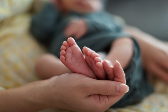 Close-up of a young woman holding a newborn baby boys feet