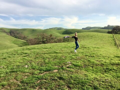 Side view of a smiling young woman dancing in the countryside, Pleasanton, California, USA