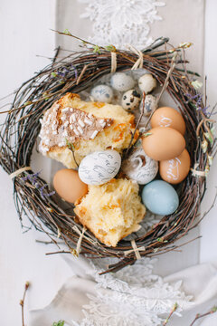 Close-up overhead view of a rustic wreath on a dining table filled with decorated Easter eggs and traditional Russian kulich Easter bread
