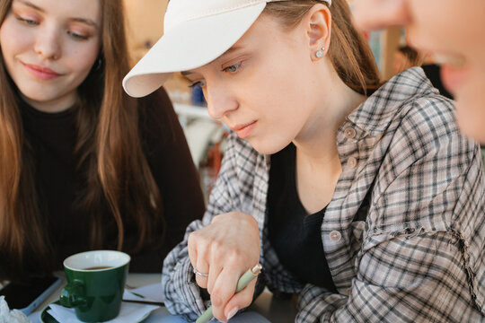 Close-up of three young women siting at a table in a cafe having a brainstorming meeting