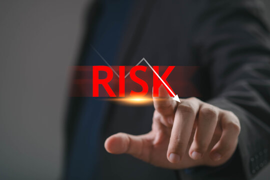 Businessman hand touching risk indicator with downward arrow representing financial loss, market volatility, investment uncertainty, crisis management, economic downturn and strategic risk assessment.