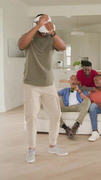 Vertical video: Starting game, man with VR headset miming objects at home entertaining friends