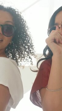 Vertical video: Dancing woman with shades and pal laughing after smartwatch tap near steps, playful