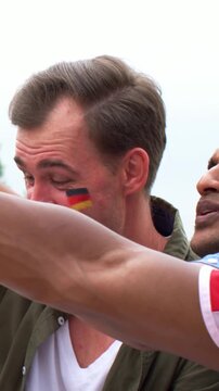 Vertical video: Raising green bottle, three men in red cheering on deck with German paint