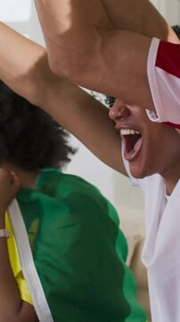 Vertical video: Reacting to live game at home, curly woman shouting, fans in jerseys, copy space