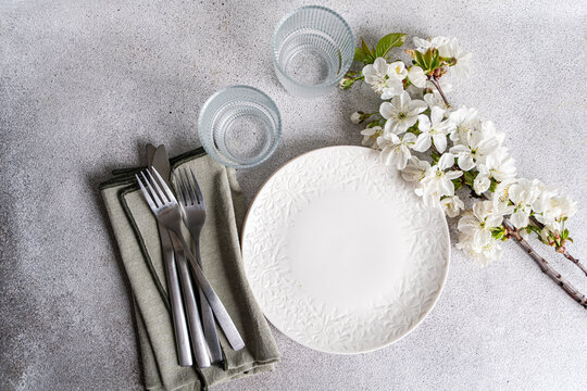 Close-up overhead view of plates, glasses, cutlery and napkins on a table with cherry blossom flowers
