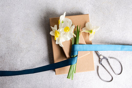 Close-up of a bunch of daffodils tied with ribbon on two cardboard Gift boxes with a pair of scissors on a table