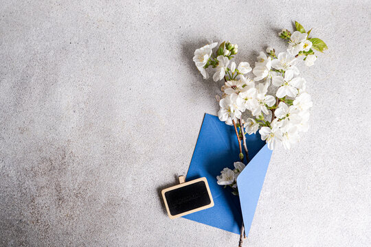 Overhead view of cherry blossom branches in an envelope with a blank chalkboard