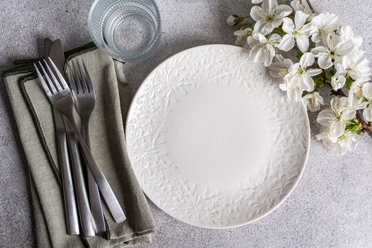 Close-up overhead view of plates, glasses, cutlery and napkins on a table with cherry blossom flowers
