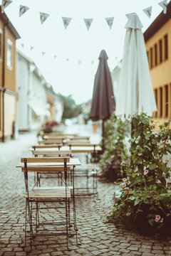 Cafe chairs and tables with parasols and bunting in a traditional cobbled street, Sweden