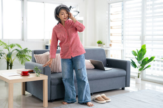 Middle aged asian woman suffering dizzy low blood pressure standing at home