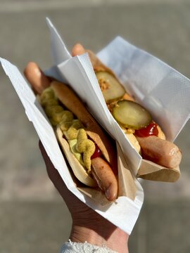 Close-up of a woman standing outdoors holding two traditional Danish hotdogs