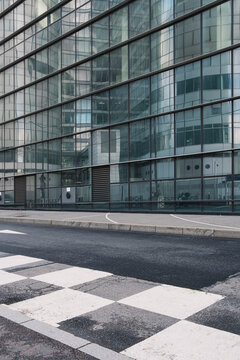 Modern glass architecture and building facades frame an empty urban street where crosswalk perspective leads through quiet infrastructure and city geometry