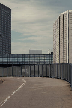 Modern office architecture lines an empty urban bridge walkway with concrete railing on a gentle curve suggesting solitude and editorial city transit