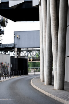 Concrete pillars frame an empty urban road underpass on a gentle curve beside sidewalk perspective depth and minimal infrastructure mood