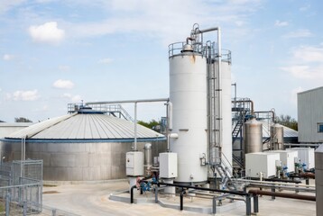 Obraz premium Industrial facility with large white storage tanks, pipes, and a domed roof structure