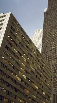 In a bustling city, towering skyscrapers stretch toward the sky. Their reflective glass surfaces capture the sunlight, creating intriguing patterns. The scene evokes a sense of modernity and energy.