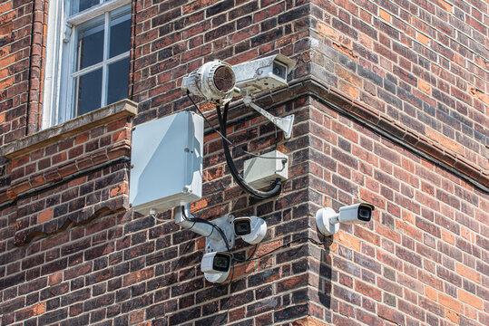 Multiple CCTV security cameras installed on the corner of a red brick building, representing urban surveillance, monitoring and public safety infrastructure. Concept of security and privacy