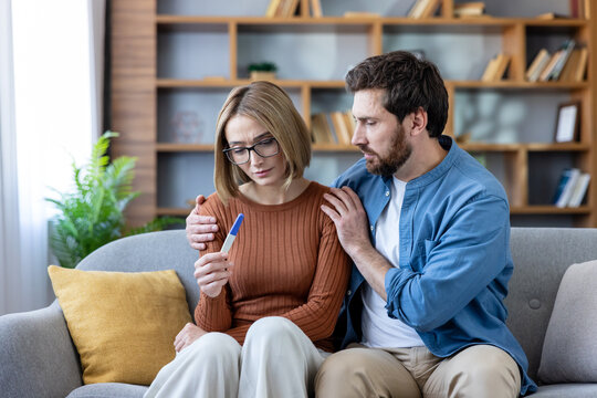 Couple getting devastating news from a negative at-home pregnancy test, a man comforting his sad wife experiencing infertility issues and disappointment while trying to conceive