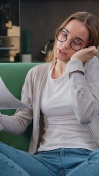 Good looking caucasian girl working with smartphone and documents collating data and checking reports of employees. Business woman makes call phone, works remotely with papers works at home, female