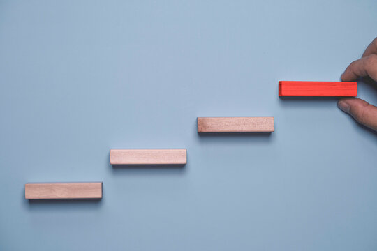 Business growth and progress concept with wooden steps and red block for career development to success , goal achievement, leadership advancement and step by step improvement in competitive market