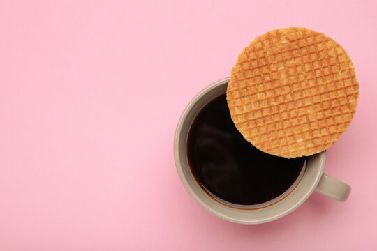 Traditional local authentic Dutch Netherlands sweet fresh homemade tasty stack brown golden waffle melt salted caramel with hot warm coffee. Stroopwafel on pink background