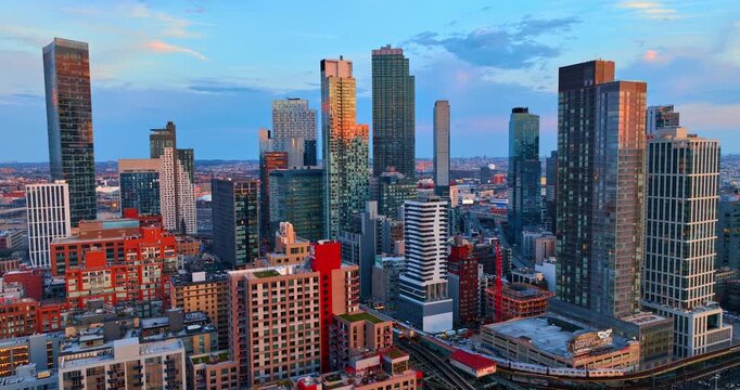 Colorful buildings of diverse design and height in the panorama of modern New York City, USA. Setting sun lights the tops of skyscrapers in the scenery.
