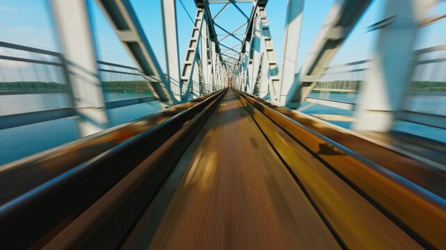Aerial FPV view of a robust metal railway bridge with rust-kissed tracks spanning vibrant blue-green waters under a bright sky, &Scaron;abac, Vojvodina, Serbia.