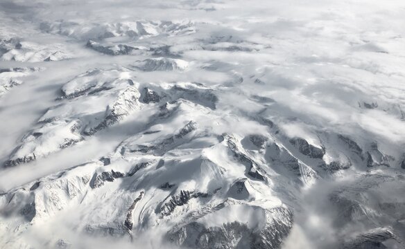 View from the plane to snow-covered mountainous landscape, bird's eye view, Greenland