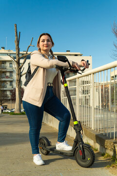 Young woman standing with electric scooter urban mobility