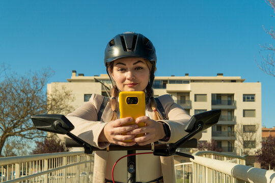 Woman riding electric scooter using smartphone