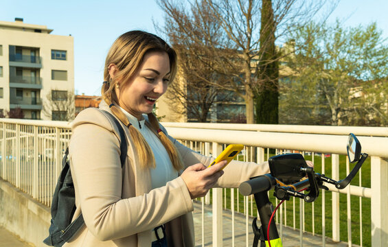 Woman smiling using smartphone with electric scooter