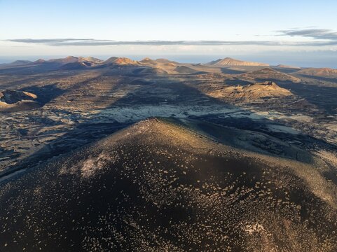 Picturesque volcanic landscape with volcanic craters and lava fields in morning light, Monta&ntilde;a Negra volcano and Volc&aacute;n de Las Nueces, Parque Natural de Los Volcanes, aerial view, Lanzarote, Canary Islands, Spain