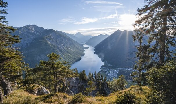 Hiking trail to Sch&ouml;nj&ouml;chl, sun shining through light pine forest, Plansee with mountains, Tyrol, Austria