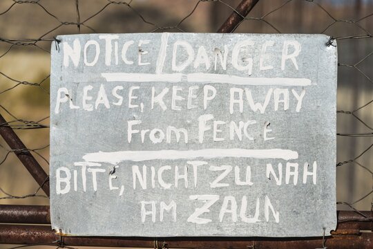 Warning sign in English and German on the fence of a predator enclosure, Namibia
