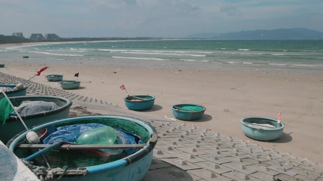 Traditional Vietnamese basket boats rest on a sandy beach in Nhon Ly, Quy Nhon, Binh Dinh, Vietnam, awaiting the next fishing expedition. The unique boats are a common sight along the coast.