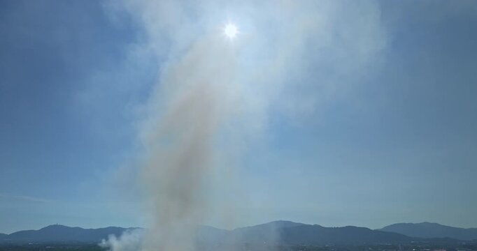 Aerial view of a landfill fire in Phuket with heavy smoke spreading across nearby landscapes and urban areas. Thick plumes of smoke rise illustrating the impact of urban waste and air pollution.