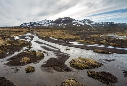 Snow-covered mountains behind a meandering river, Sn&aelig;fellsnes Peninsula, West Iceland, Iceland