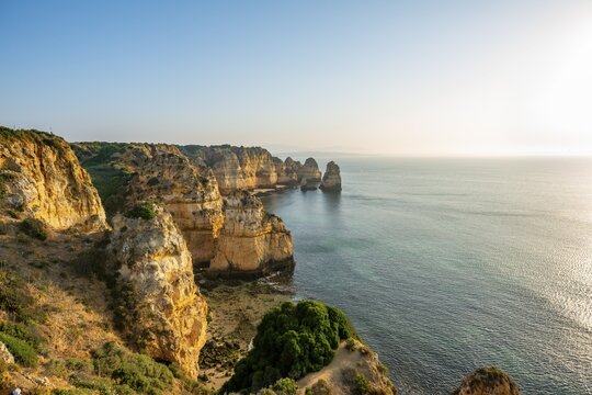 Rugged rocky coast with cliffs of sandstone, rock formations in the sea, morning light, Ponta da Piedade, Algarve, Lagos, Portugal