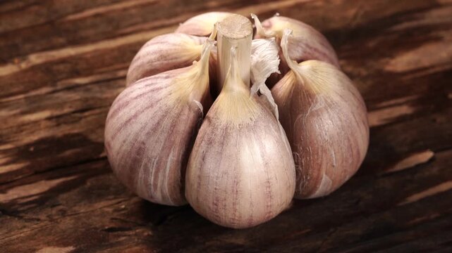 A head of garlic slowly turns on a vintage wooden surface.